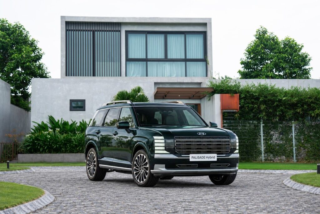 Hyundai Palisade Hybrid màu xanh đậm đỗ trước dãy nhà hiện đại